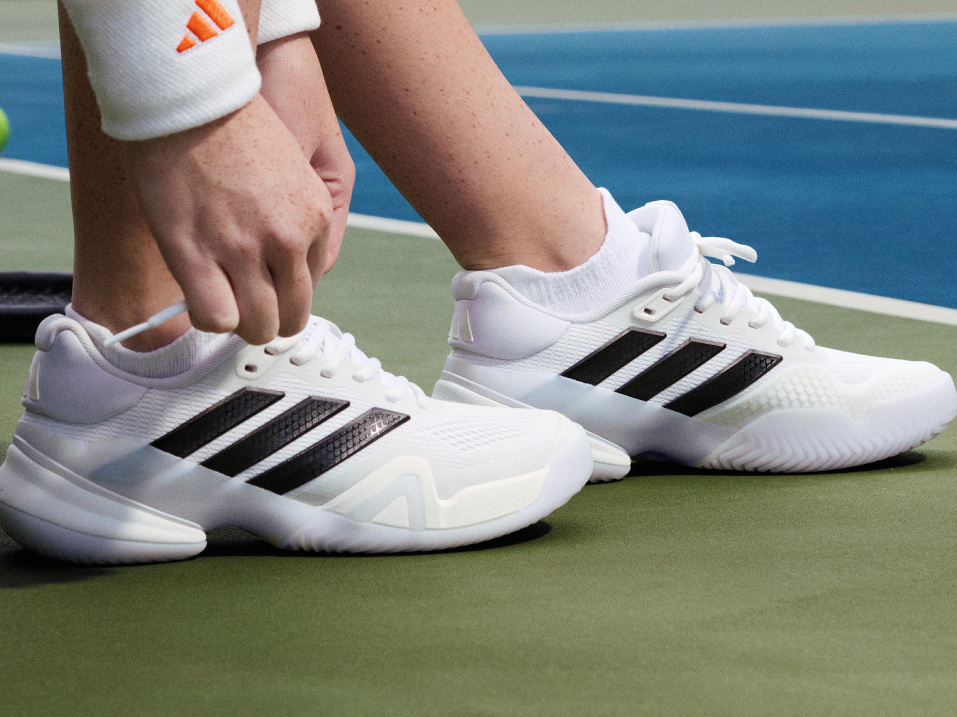 Close view of a player adjusting the laces of white and black adidas Barricade 14 tennis shoes